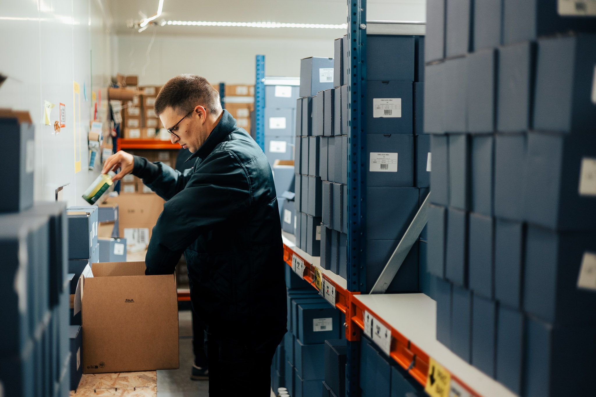 Un salarié qui prépare un colis composé de bouteilles de jus de fruit