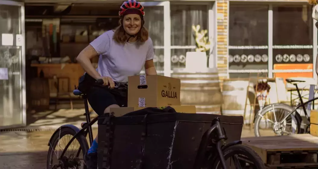 Coursier femme à vélo cargo avec casque rouge